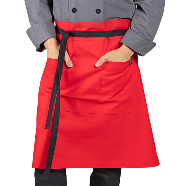 A person wearing a red Uncommon Chef waist apron with black trim.