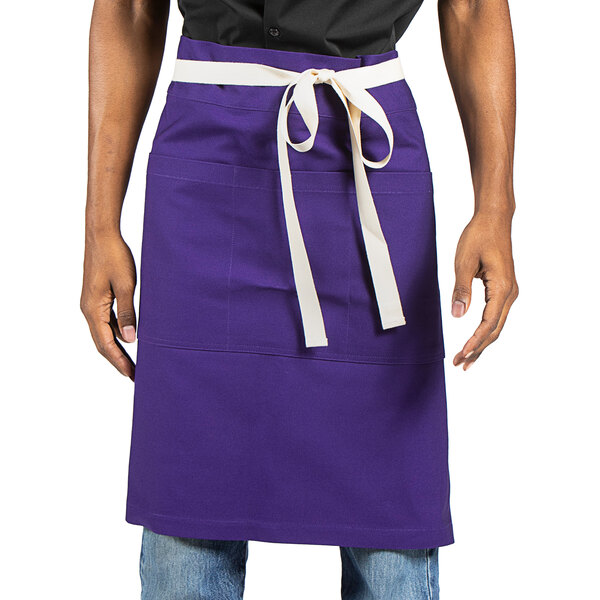 A man wearing a Uncommon Chef purple waist apron with white ribbon.