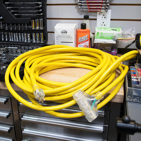 A yellow DuroMax extension cord with three plugs on a table.