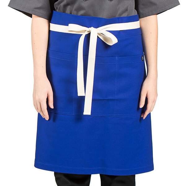 A woman wearing a royal blue Uncommon Chef waist apron with white webbing.