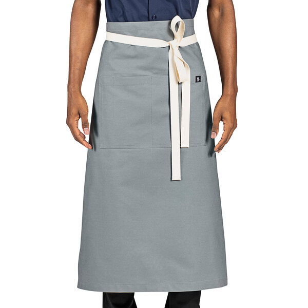 A person wearing a grey Uncommon Chef bistro apron with natural webbing.