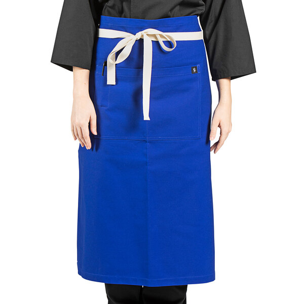 A woman wearing a royal blue Marvel bistro apron with natural webbing.