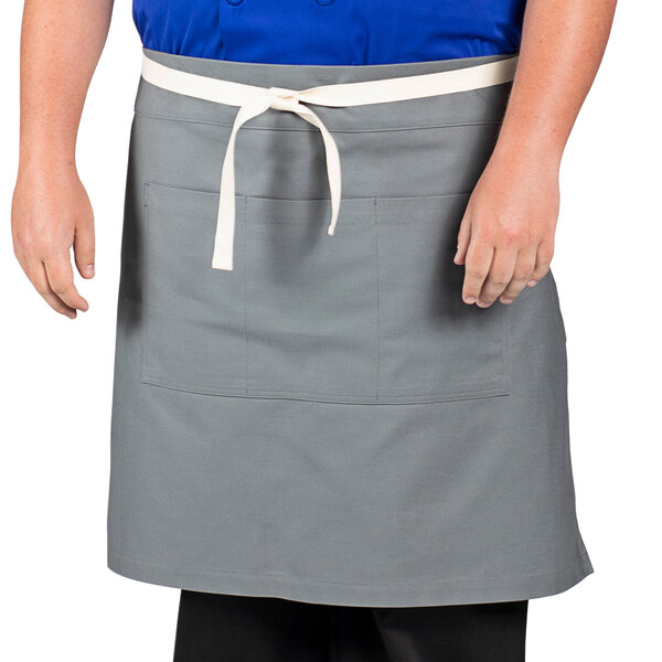 A man wearing a gray Uncommon Chef waist apron with white webbing.