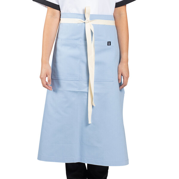 A woman wearing a blue Uncommon Chef bistro apron with natural webbing.