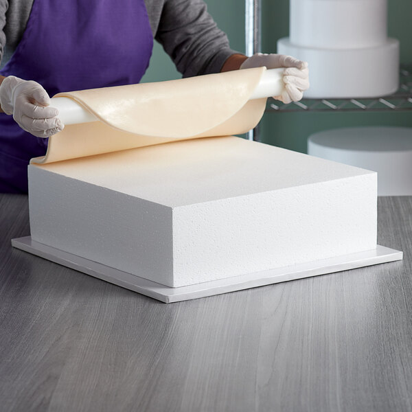 A woman rolls a piece of paper on a Baker's Mark foam square.