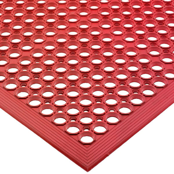A bagged red rubber San Jamar floor mat with holes in it.