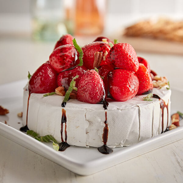 A white cake with whole strawberries and chocolate drizzled on top.
