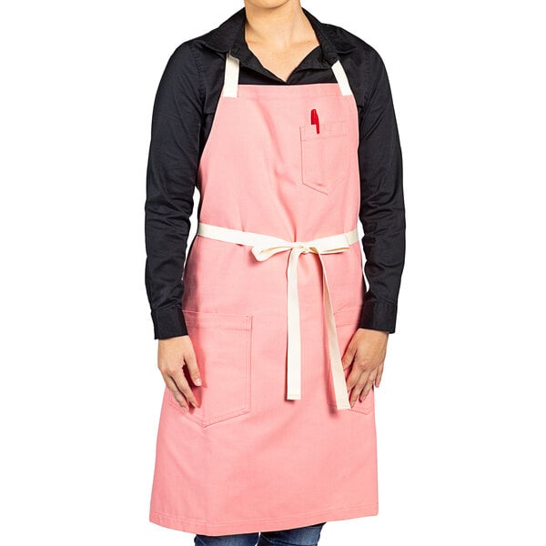A woman wearing a coral pink Uncommon Chef apron.