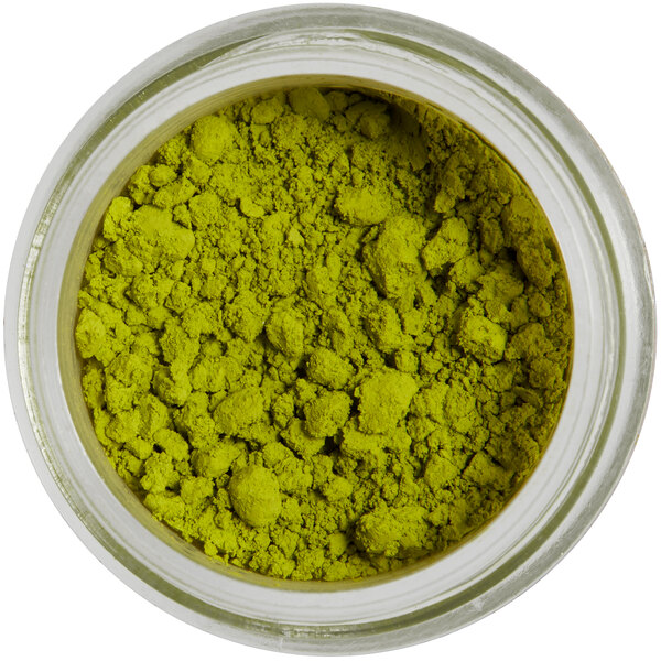 A jar of powdered green petal dust with a white label.