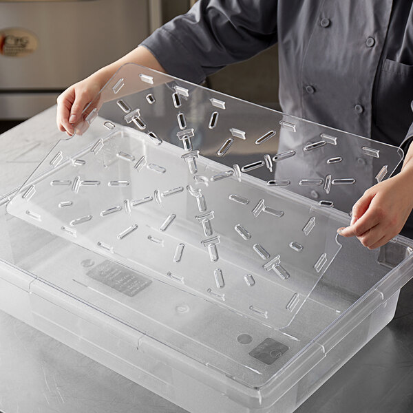 A person holding a clear plastic container with a drain tray.