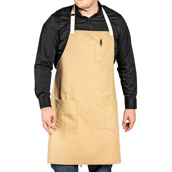 A man wearing a light beige Uncommon Chef bib apron with natural webbing.