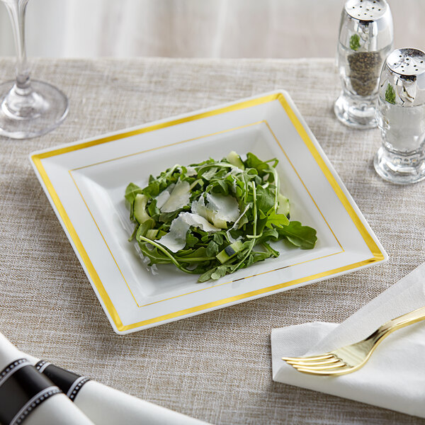 A Visions ivory plastic square plate with a salad on it on a table.