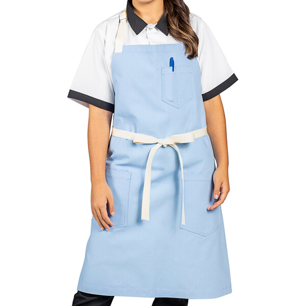 A woman wearing a sky blue Uncommon Chef bib apron.