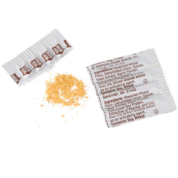 A No Salt Flavor Sprinkles seasoning portion packet next to a small pile of yellow seasoning.