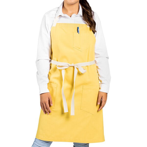 A woman wearing a yellow Uncommon Chef bib apron with natural webbing.