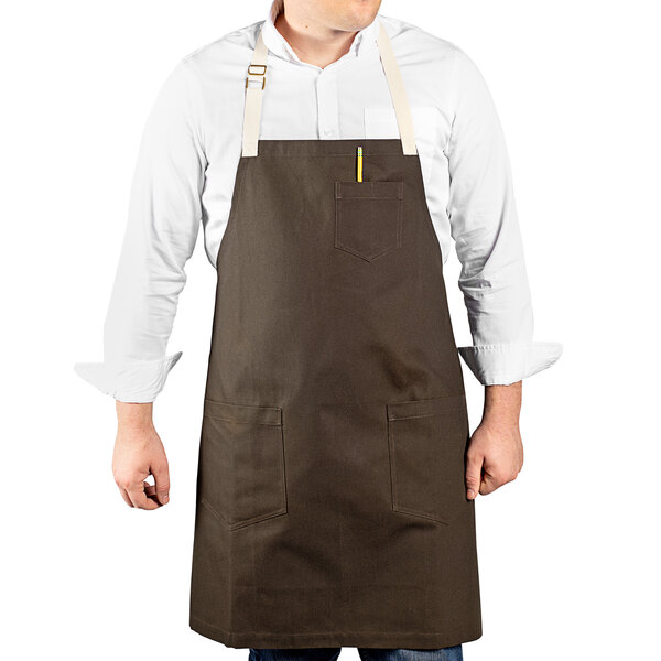 A man wearing a dark brown Uncommon Chef apron with natural webbing.