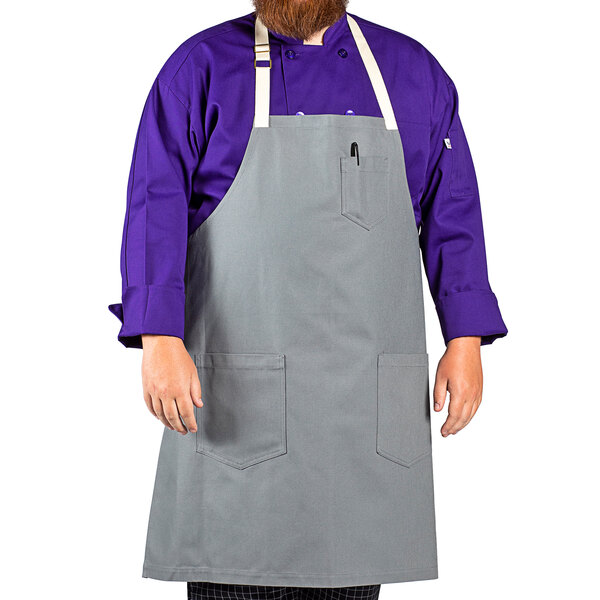 A man wearing a Uncommon Chef gray canvas bib apron.