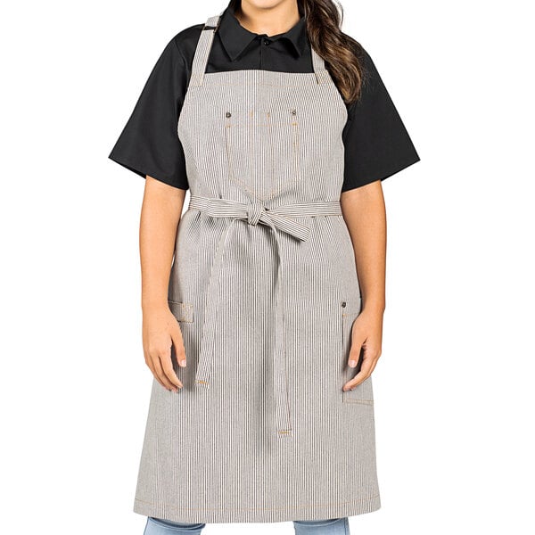 A woman wearing a Uncommon Chef denim apron with towel loop and pockets.