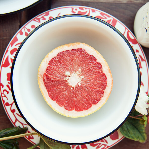 A half of a grapefruit in a white Crow Canyon Home enamelware bowl with a black rim.