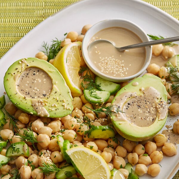 A plate of food with chickpeas, avocado, and tahini dressing.