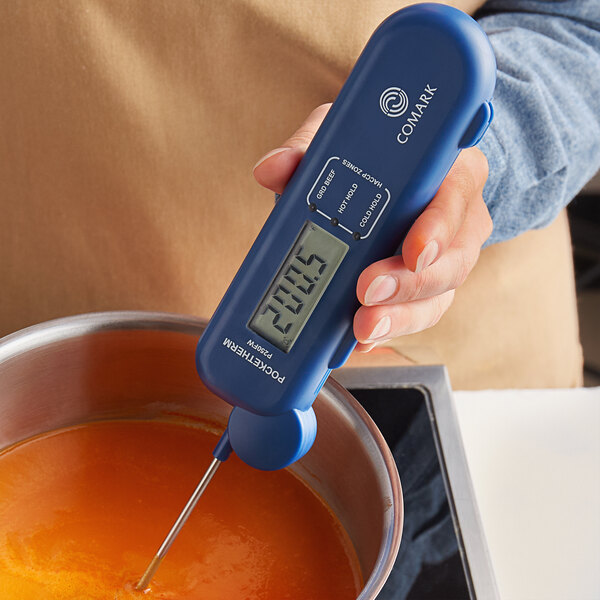 A person using a Comark Pocketherm waterproof folding thermocouple thermometer to measure liquid in a bowl.
