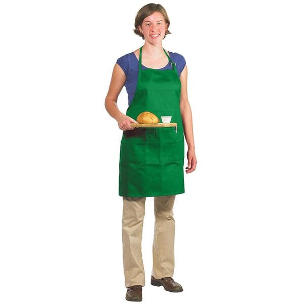 A woman wearing a green Chef Revival apron holding a tray of bread.