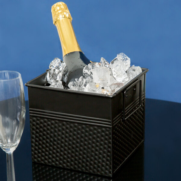 An American Metalcraft black metal square beverage tub with ice holding a bottle of champagne.