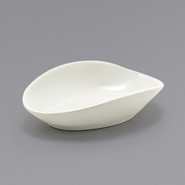 A Front of the House Tides white scallop oval ramekin on a gray surface.