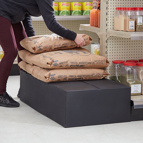 A woman putting brown bags on a black plastic Regency stacker.
