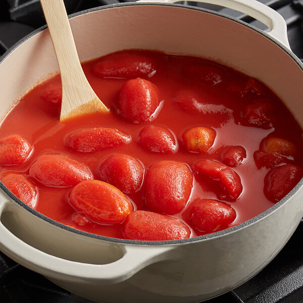 A pot of whole peeled tomatoes with a wooden spoon.