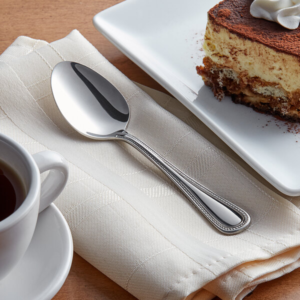 A spoon on a plate with a piece of cake.
