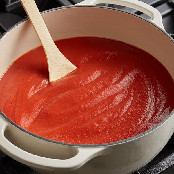 A pot of Bella Vista tomato puree with a wooden spoon in it.