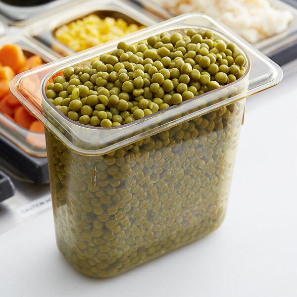 A close-up of a clear Cambro H-Pan filled with peas and carrots.