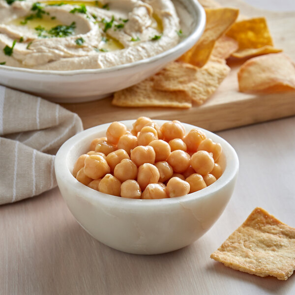 A bowl of hummus next to a bowl of Furmano's Chickpeas.