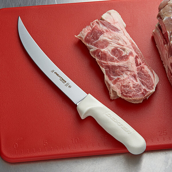 A Dexter-Russell Sani-Safe narrow breaking knife on a cutting board next to meat.