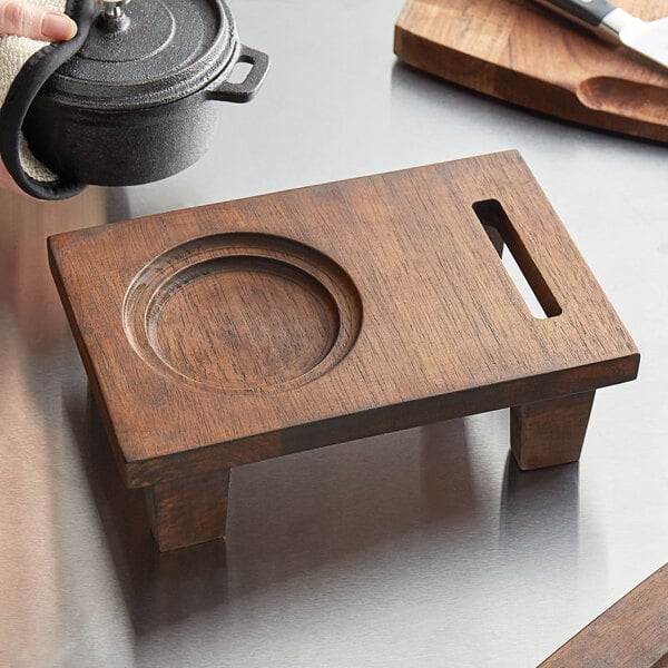 A Valor rubberwood display stand with a wooden cutting board and a pot on it.