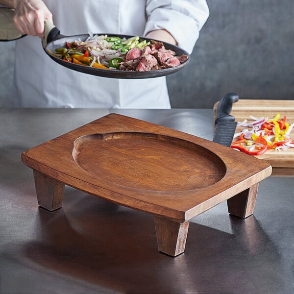 A person using a Valor Rustic Chestnut display stand to serve food on a table.