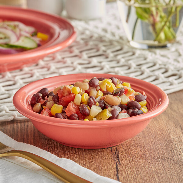 A close up of an Acopa Capri coral stoneware fruit bowl filled with beans and corn on a table.