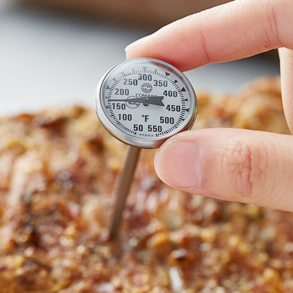 A person using a Comark pocket probe thermometer to check the temperature of meat.