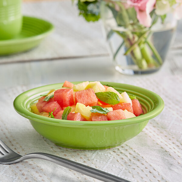 A green Acopa Capri stoneware bowl filled with watermelon slices.