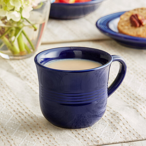 An Acopa Capri deep sea cobalt stoneware cup on a table with a drink in it.