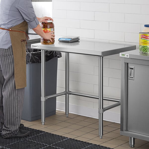 A man standing at a Regency stainless steel work table in a kitchen.