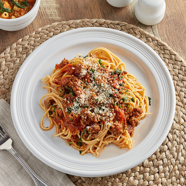 A white Acopa Capri stoneware plate with spaghetti and meat sauce and a fork.