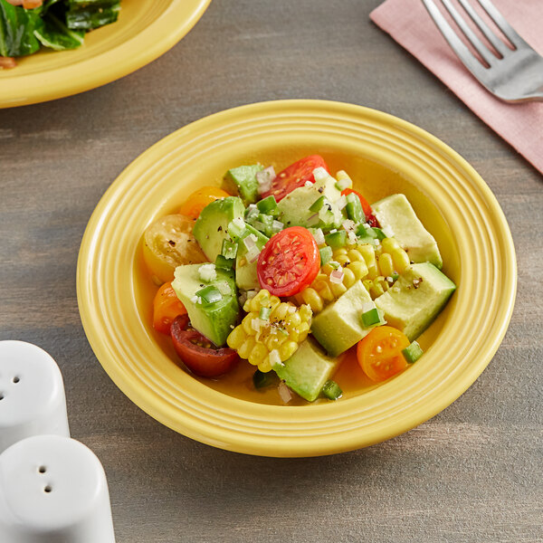 A yellow Acopa Capri stoneware plate with a salad on it and a fork.