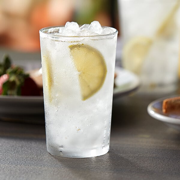 A Duralex glass of ice water with a lemon slice.