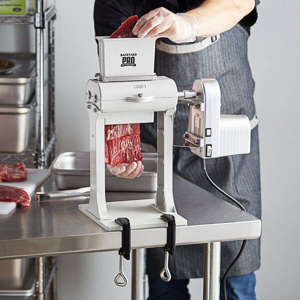 A man uses a Backyard Pro electric meat tenderizer to tenderize meat.