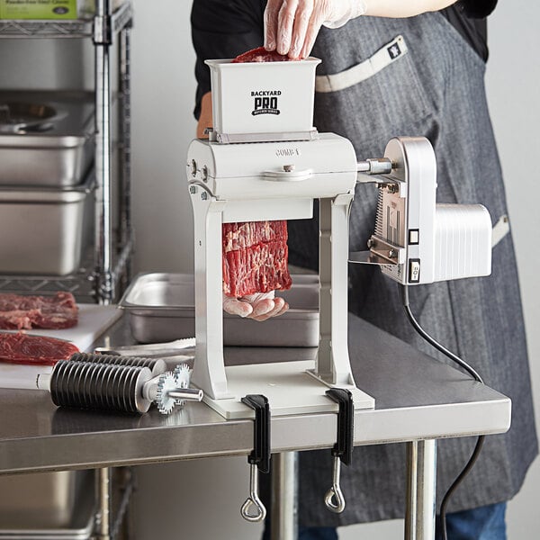 A man using a Backyard Pro meat tenderizer to cut meat.