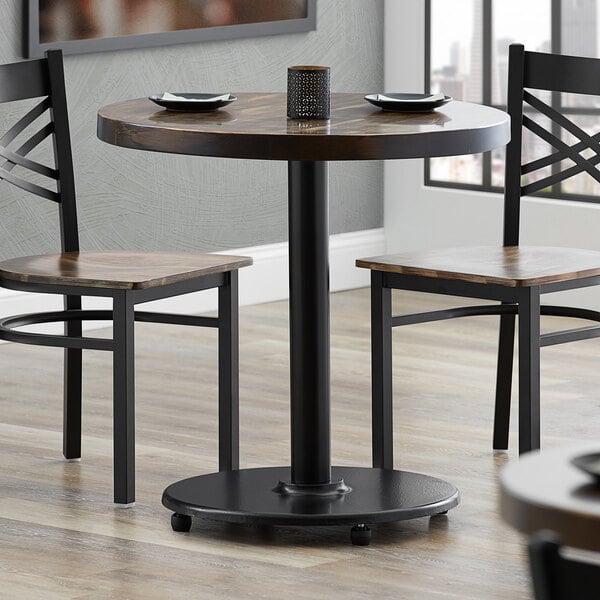 A black Lancaster Table & Seating cast iron table base with two chairs.