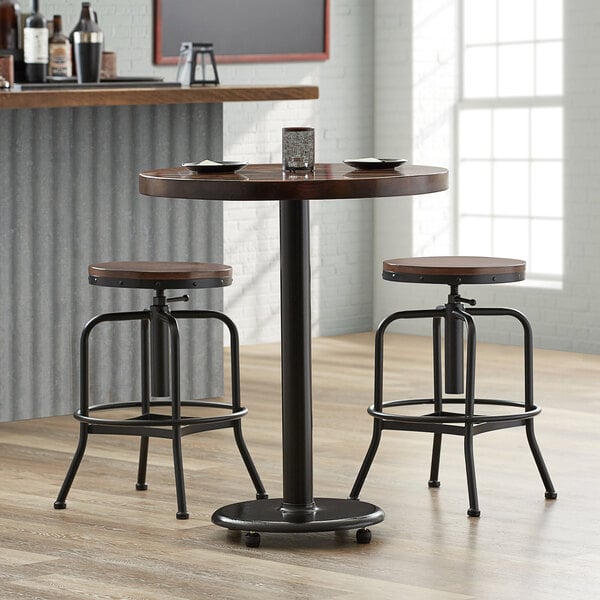 A Lancaster Table & Seating cast iron counter height table base with FLAT Tech levelers on a round table with wooden stools.