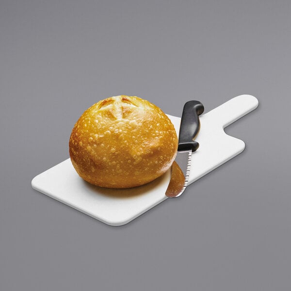 A bread roll and knife on a Tomlinson white bread board.